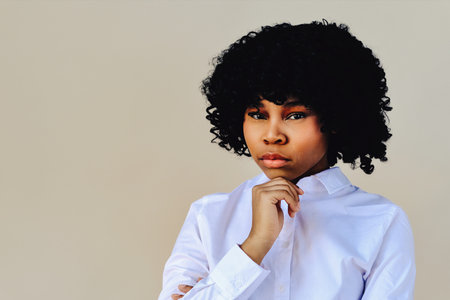 woman with hand o chin thinking, looking at camera, studio shotの写真素材