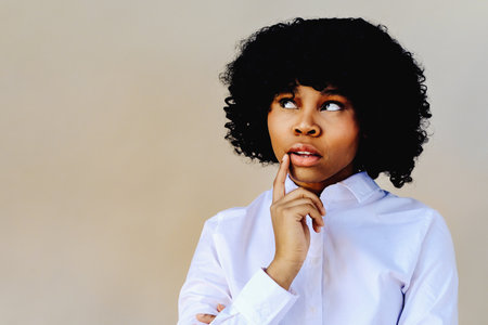 woman with hand o chin thinking, looking away at copy space, studio shotの写真素材