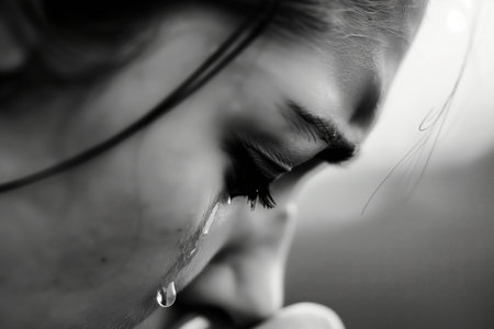 A woman with her eyes closed and tears in her eyes. She is crying. Scene is sad and emotionalの素材