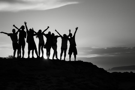 A group of people are standing on a hill, with the sun shining on them. They are all smiling and seem to be enjoying each other's companyの素材