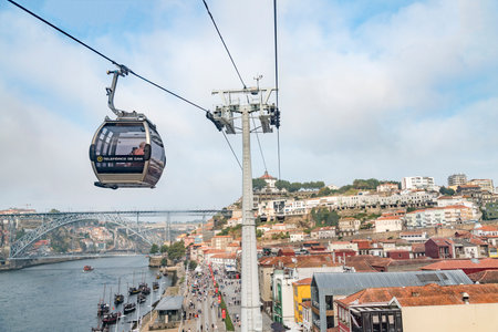 A cable car is suspended above Porto near the river. The cable car is carrying passengers.の写真素材
