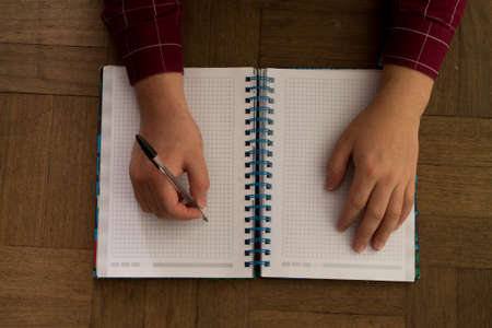 A man writes in his notebook with his right hand.の写真素材