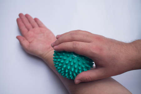 A man massages his left forearm with a massage ball.の写真素材