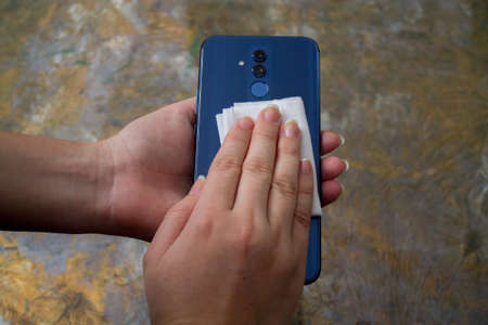 A woman disinfects her cell phone.