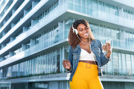 Woman smiling in video call with head phones on the streetの写真素材