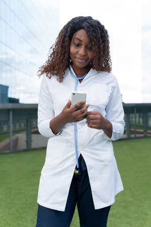 Afro female doctor looks surprised at a message on her cell phone. High quality photoの写真素材