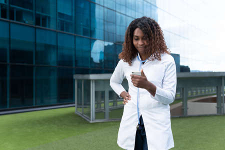 Latin female doctor watches worried her cell phone in the street. High quality photoの写真素材