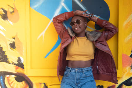 portrait of an afro girl in the street looking happy with sun glasses and colorful oufit. High quality photoの写真素材
