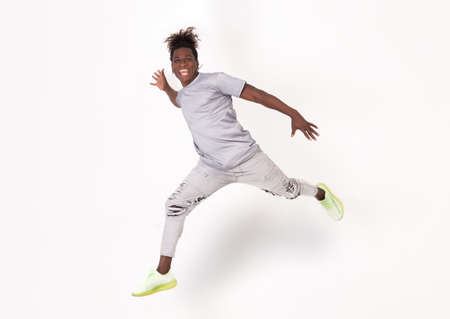 Happy young smiling afro american jumping in front of a white or grey background. High Quality...