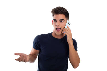 young handsome man having an effusive conversation by phone mobile in a photo studio. He is wearing a tight blue t-shirtの写真素材
