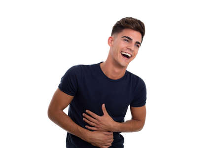 young handsome man laughing in a photo studio. He seems very happy. He is wearing a tight blue...