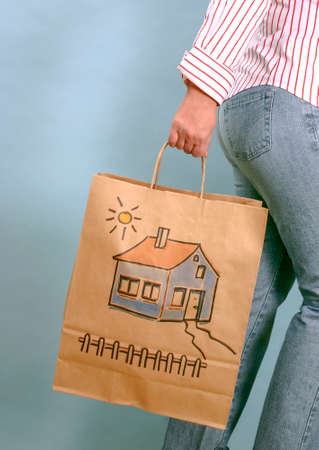 Unrecognizable woman holding brown paper bag. To buy a house.の写真素材