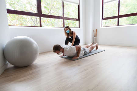 Beginner yogi and his coach practicing yoga wearing protective mask during covid-19の写真素材