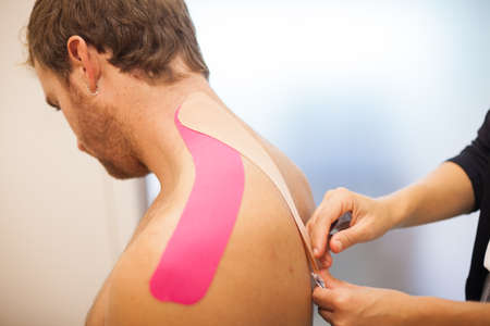 shoulder treatment with pink physio tape