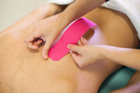 Back treatment with pink physio tapeの写真素材