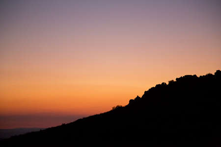 Silhouette sunset over marked orange background and violet colorsの写真素材