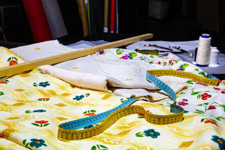 Sewing workshop with a table full of fabrics of various colors and patterned textures, ready for cutting and makingの写真素材