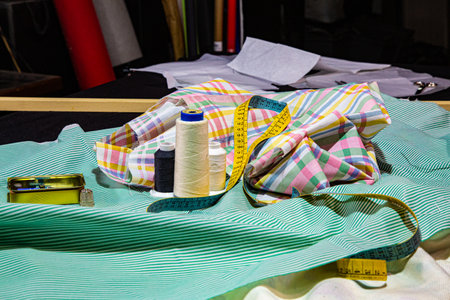 Sewing workshop with a table full of fabrics of various colors and patterned textures, ready for cutting and makingの写真素材