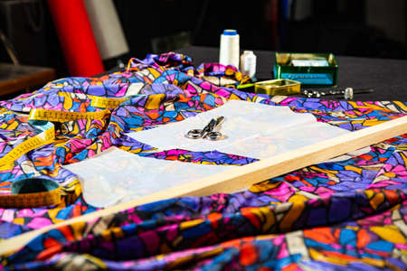 Sewing workshop with a table full of fabrics of various colors and patterned textures, ready for cutting and makingの写真素材