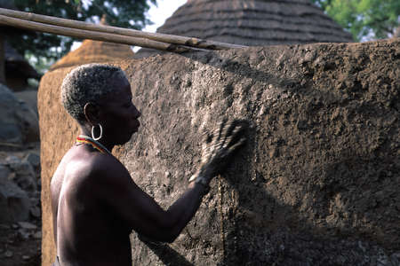 SENEGAL. Tambacounda Region  Bassari Country  BEDIK  " Village of Iwol " ; Old woman  applying mud to his hut のeditorial素材