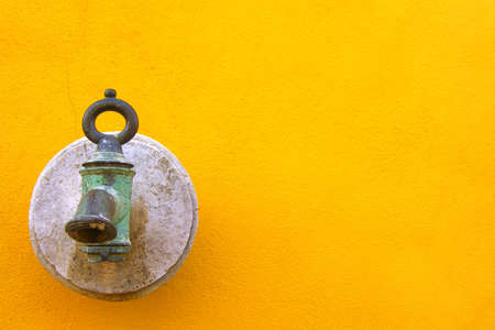 Old metalic waterspout on yellow backgroundの写真素材