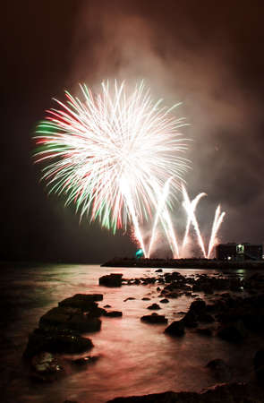 White fireworks launched at the shoreline of the harbor の写真素材