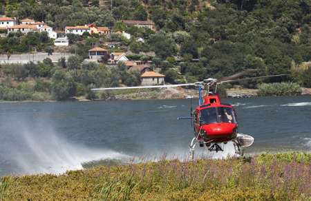 Firefighting helicopter on a collecting water in the riverの写真素材