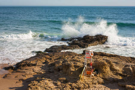 Rescue station on the beach with a wave-busting in the rock as backgroundの写真素材