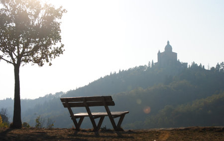 Wooden bench on the hillside in the morning with church in the backgroundの写真素材