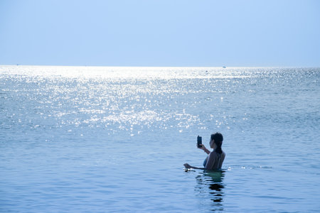 Asian woman happy and taking a photo at the seaの写真素材