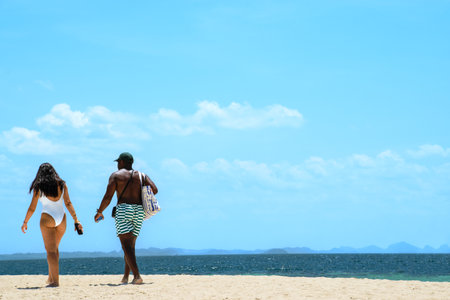 Black and Latin couple walking along the beach on holidaysの写真素材