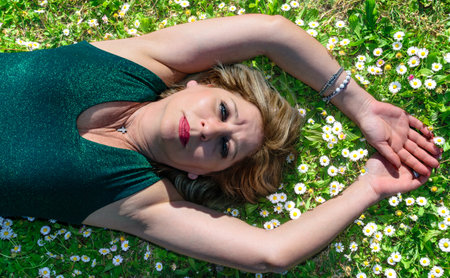 Mature woman lying in grass with margheritesの写真素材