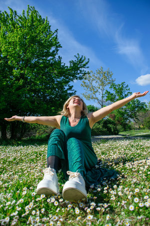 Mature happy woman in the in grass with marguerites. Menopause and mothers day conceptの写真素材