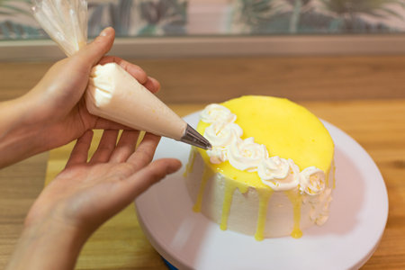 Hands decorating and preparing lemon cake. The concept of homemade and professional pastry.の写真素材