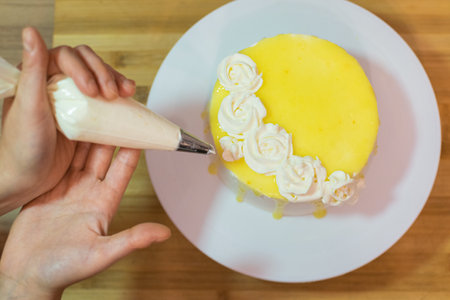 Hands decorating and preparing lemon cake. The concept of homemade and professional pastry.の写真素材