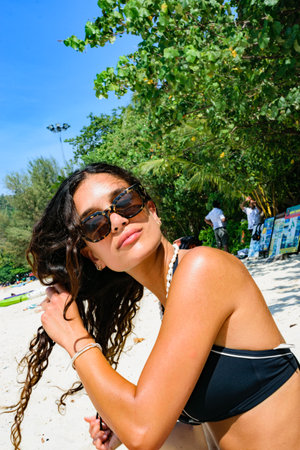 Gorgeous Lebanese young woman on beach posing with sunglasses touching his hairの写真素材