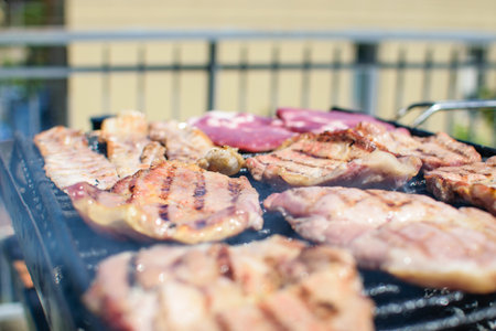 Steaks and bacon cooking on smoking barbecue on terrace.の写真素材