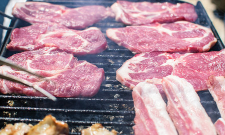 Steaks and bacon cooking on smoking barbecue on terrace.の写真素材