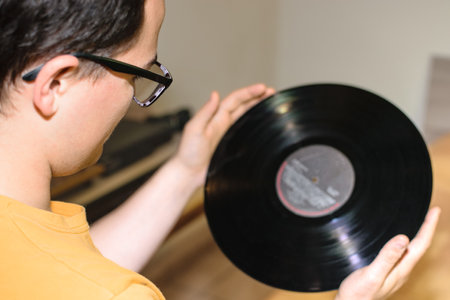Young man with glasses enjoying while contemplating his vinyl record in his roomの写真素材