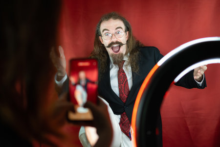 Funny Caucasian Man posing at photography studio while being shot by cell phoneの写真素材