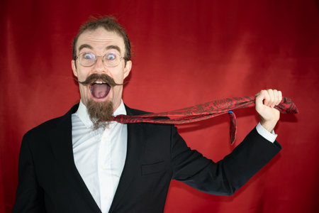 Funny man pulling his tie screaming while expressing various emotions comicallyの写真素材