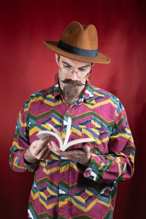Vintage Hipster man with glasses, hat and mustache watching a bookの写真素材