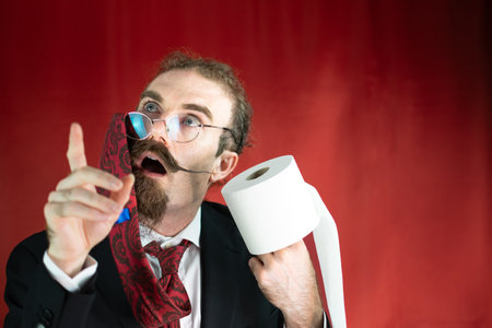 Funny man with glasses, red tie on his head and toilet paper in hand looking upの写真素材