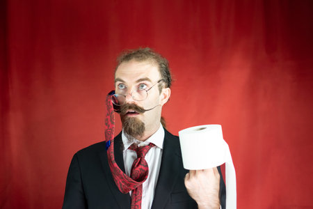 Stunt man with glasses, red tie on his head and toilet paper in hand looking upの写真素材