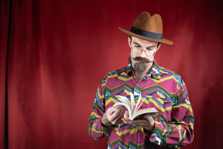 Vintage Hipster man with glasses, hat and mustache watching a bookの写真素材