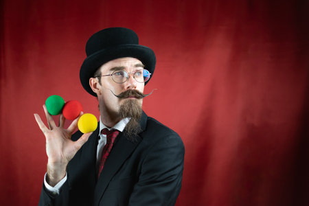 Vintage Caucasian Magician with top hat, glasses and mustache with colored ballsの写真素材