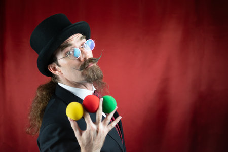 Vintage Caucasian Magician with top hat, glasses and mustache with colored ballsの写真素材
