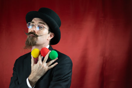 Vintage Caucasian Magician with top hat, glasses and mustache with colored ballsの写真素材