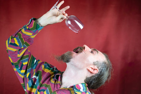 Hipster man with mustache drinking wine in stylish way raising glass satisfied