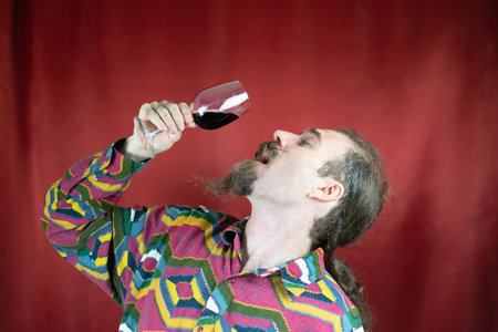 Hipster man with mustache drinking wine in stylish way raising glass satisfiedの写真素材